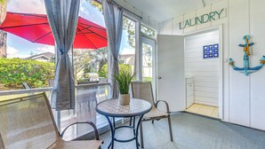 Een kamer met een ronde tafel, stoelen, een potplant en een deur met de tekst 'laundry'.