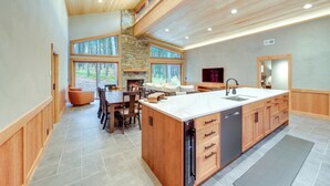 A spacious kitchen with a large island, wooden cabinetry, and a stone fireplace.
