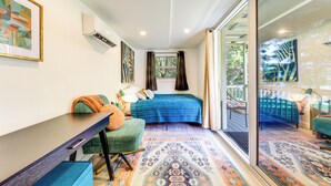 A compact bedroom with a bed, a desk, and a chair. There is a window with curtains, a door leading to a balcony, and a patterned rug. - Tropical Pool Oasis on 1/4 Acre by Downtown Stuart (Stuart)