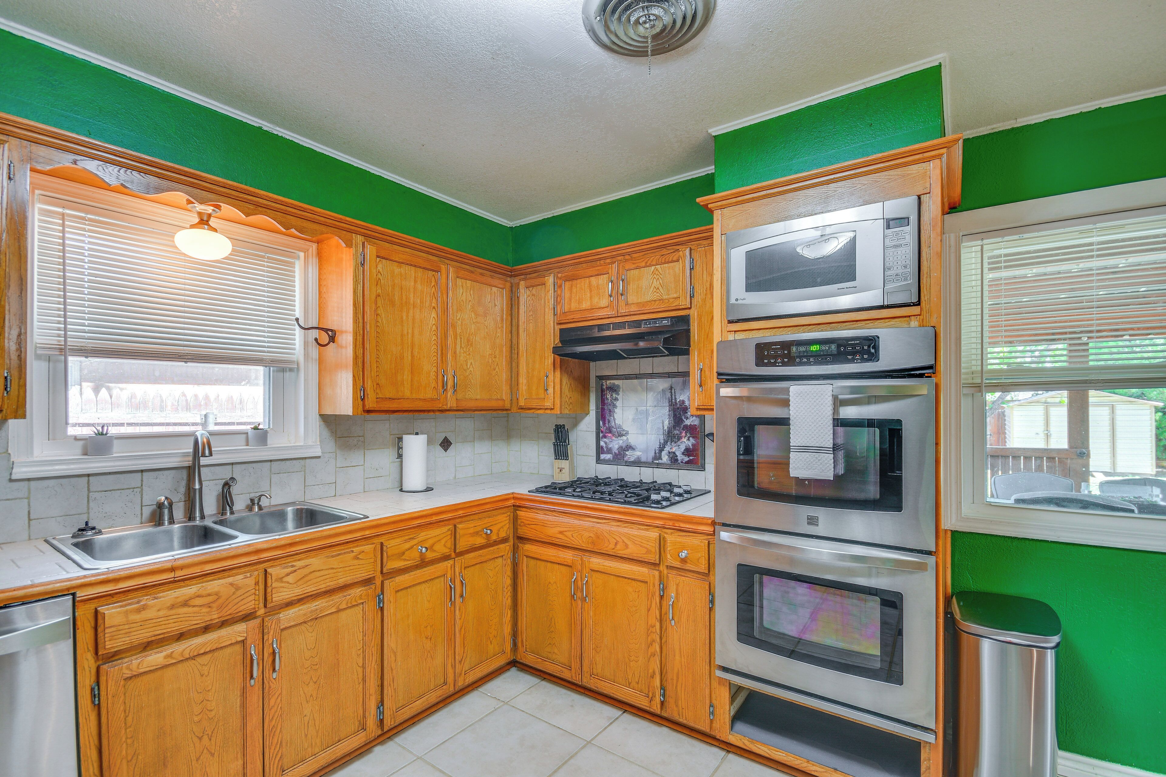 Una cocina con armarios de madera, electrodomésticos de acero inoxidable y una pared de acento verde.