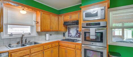 Una cocina con armarios de madera, electrodomésticos de acero inoxidable y una pared de acento verde.