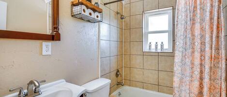 Une salle de bain équipée d’un lavabo, de toilettes, d’une baignoire et d’un rideau de douche.
