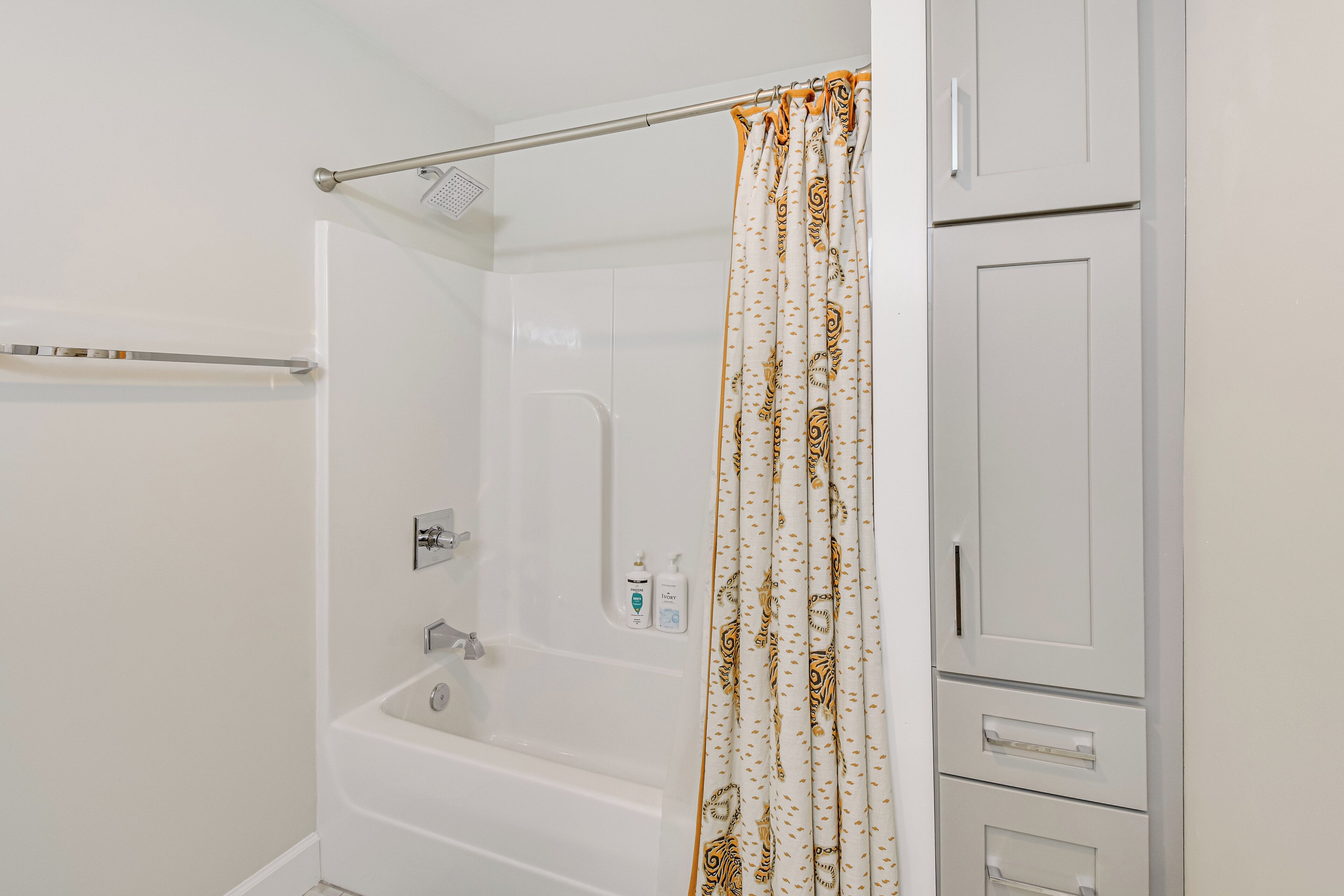 Un baño con bañera, cortina de ducha y secador de manos.