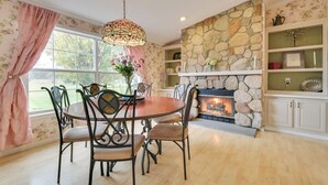 Un comedor con chimenea de piedra, piso de madera y una lámpara de araña.