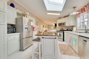 A modern kitchen with white cabinetry, stainless steel appliances, and a central island.
