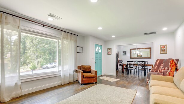 Un salon avec un canapé, un fauteuil et une table à manger avec des chaises.