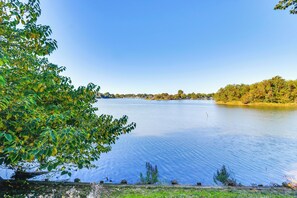Un lago tranquilo con cielo despejado y árboles en primer plano.