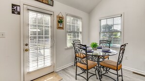 A dining area with a round table, four chairs, and a window with blinds.