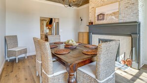 A dining area with a wooden table, woven chairs, a chandelier, and a fireplace. - Hope Retreat w/ Furnished Deck Near Parks! (Hope)