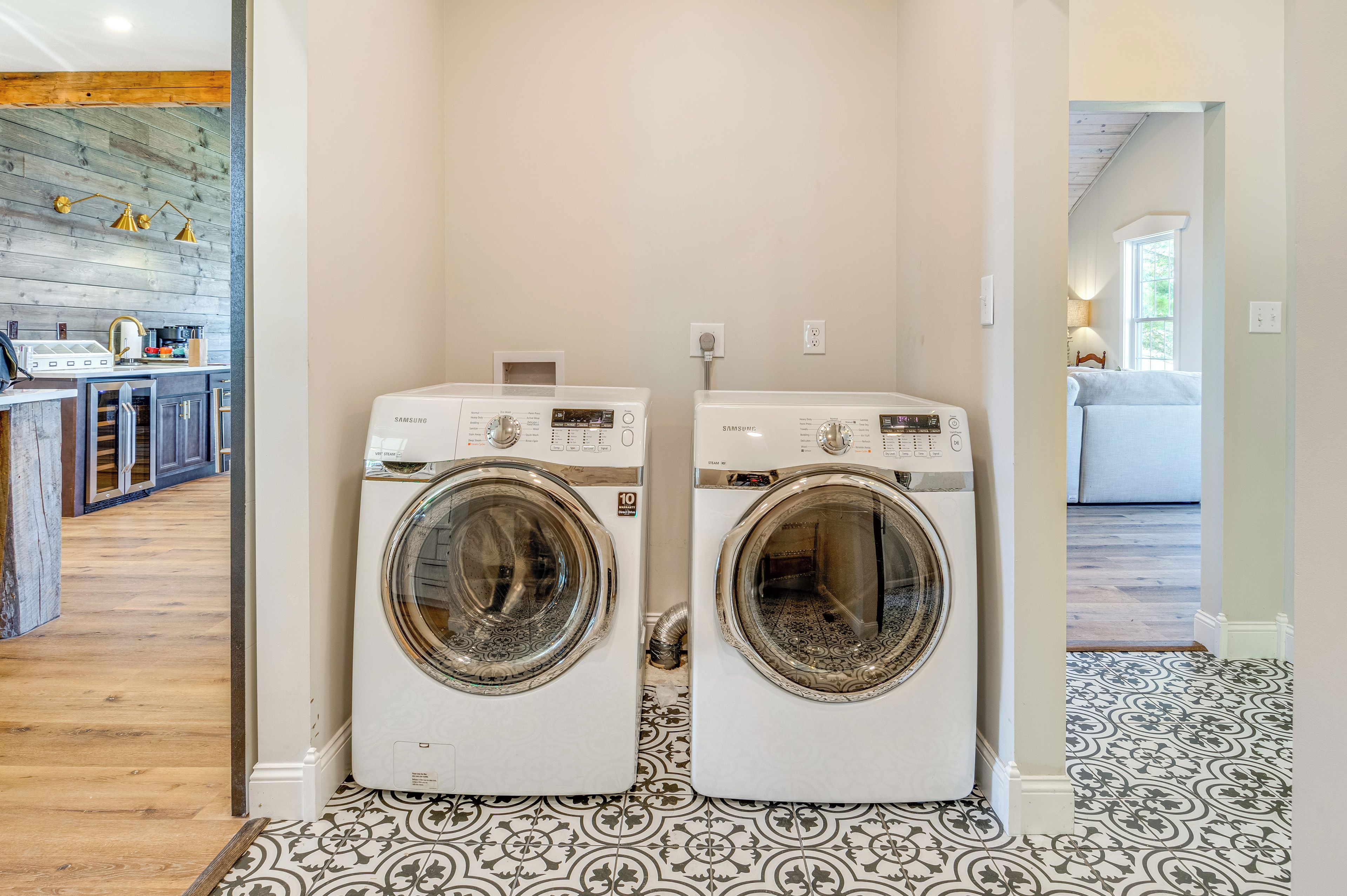 A laundry room with two white front-loading washing machines, a wooden floor, and a patterned tile floor.