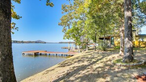 A lakeside property with a dock, a covered seating area, and a building with a yellow facade. - 10 Mi to National Park: Patio at Hot Springs Home (Hot Springs)