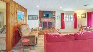 A living room with a brick fireplace, a television mounted above it, and a red couch. - 10 Mi to National Park: Patio at Hot Springs Home (Hot Springs)