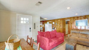 A cozy living room with a red sofa, a beige sofa, a wooden dining table, and a kitchen area in the background. - 10 Mi to National Park: Patio at Hot Springs Home (Hot Springs)
