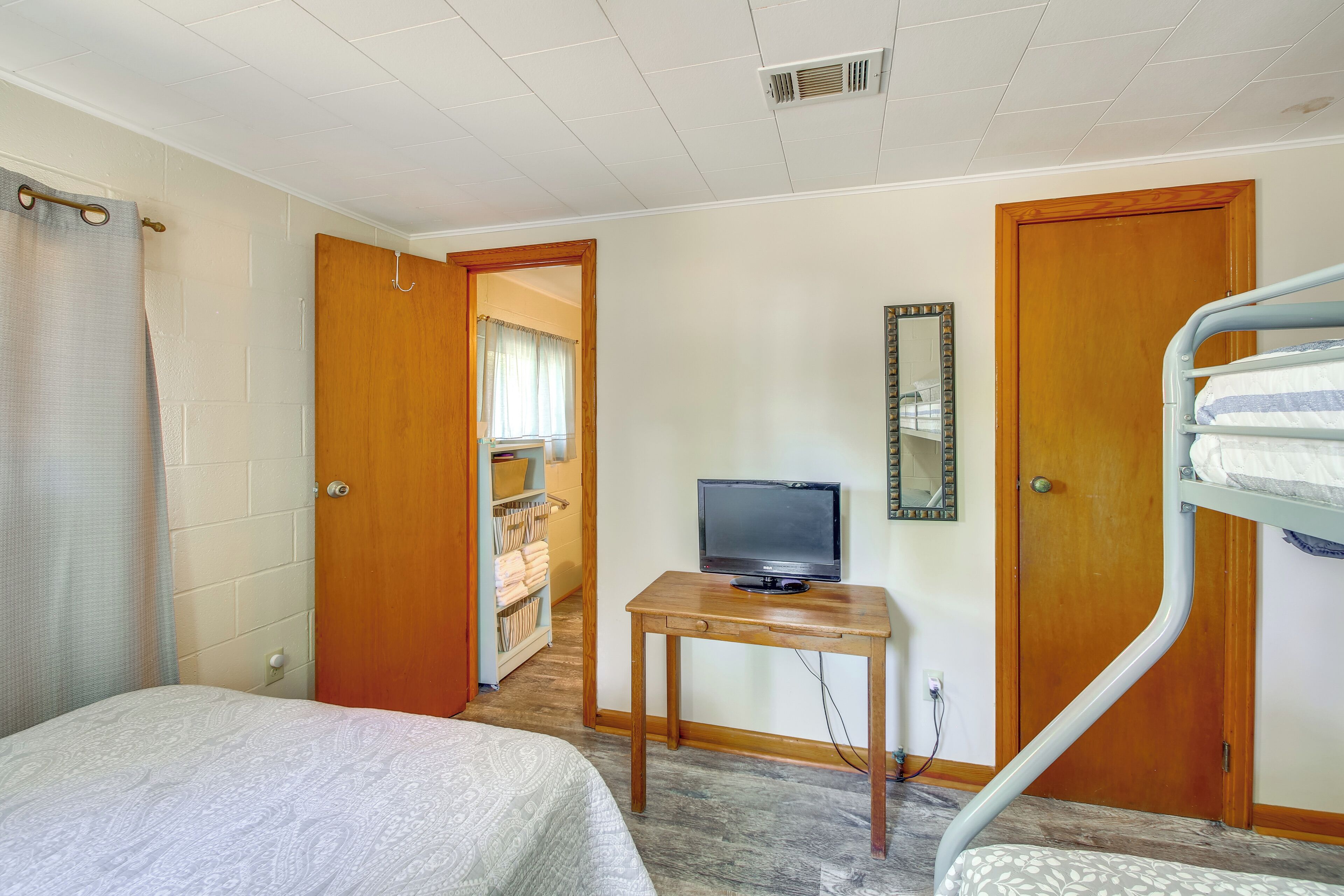 A bedroom with a bed, a TV on a wooden table, a bunk bed, and a wardrobe.