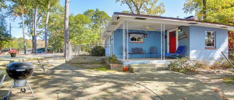A small house with a porch, a barbecue grill, and a patio area.