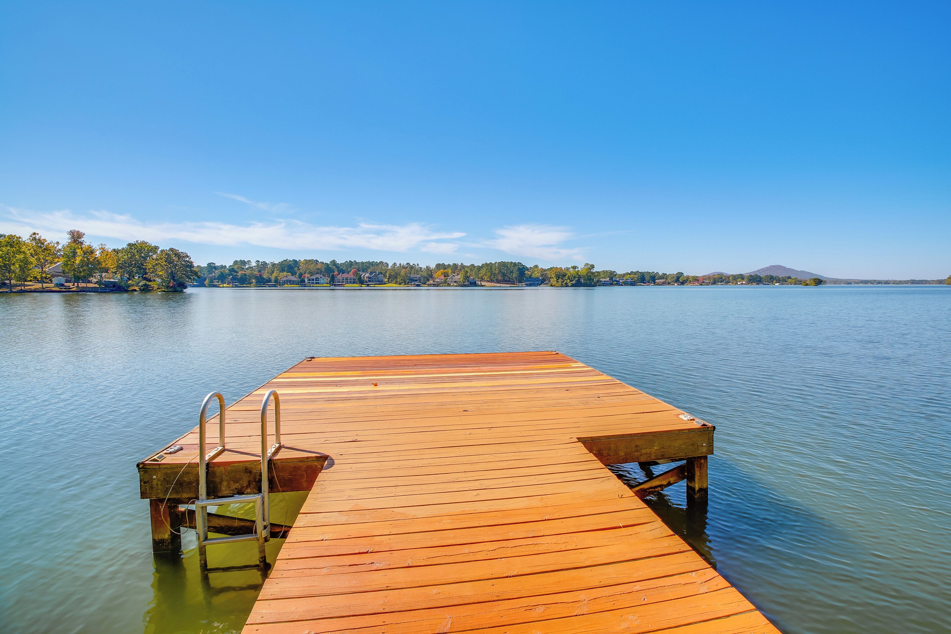 A wooden dock extending into calm water with a clear sky above.
