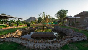 Un jardin aménagé avec une fontaine centrale, entouré de murs en pierre et de verdure.