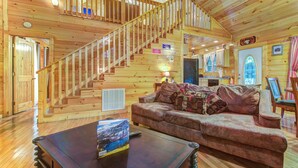 L’intérieur d’une cabane en bois comprend un escalier, un salon avec un canapé et une table basse, ainsi qu’un coin cuisine.