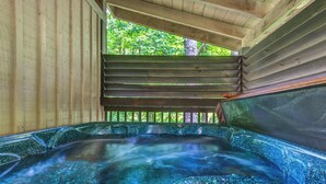 Un bain à remous avec une terrasse en bois et une vue sur les arbres.