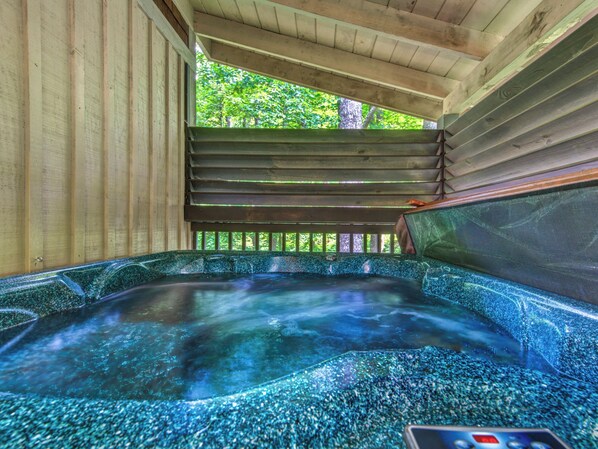 A hot tub with a wooden deck and a view of trees. - 1BR, hot tub, jacuzzi.  Free attraction tickets! (Gatlinburg)