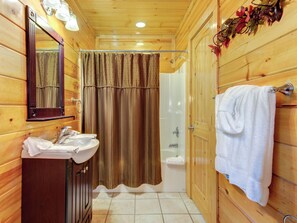 A wooden bathroom with a sink, mirror, shower, and towel rack. - 1BR, hot tub, jacuzzi.  Free attraction tickets! (Gatlinburg)