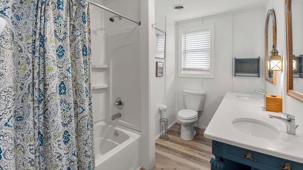 Une salle de bain avec douche, toilettes et meuble-lavabo à deux vasques.