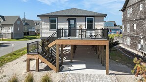 Une maison à deux étages dotée d’une terrasse en bois et d’un escalier menant à l’étage supérieur.