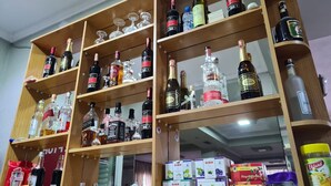 A liquor store with shelves stocked with various bottles and boxes of alcohol. - Tirane Tranquility Cottage (Paskuqan)