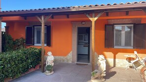 A house with an orange facade, a tiled roof, and a small garden with two statues. - la casetta di zio e pia (Fiumicino)