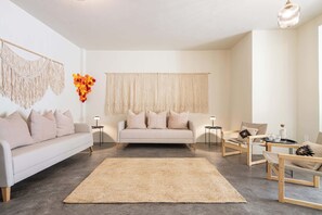 Ein modernes Wohnzimmer mit einer Couch, zwei Sesseln, einem Couchtisch und einem großen Teppich.