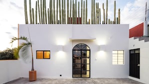 A modern building with a cactus garden, a black arched entrance, and a white facade. - Casa Lumos - Minimalist Comfort Suites in Centro Historico (Oaxaca de Juárez)