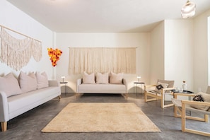 A modern living room with a sofa, two chairs, a coffee table, and a large rug. - Casa Lumos - Minimalist Comfort Suites in Centro Historico (Oaxaca de Juárez)