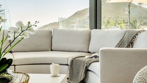 Ein modernes Wohnzimmer mit einem beige gefärbten Sofa, einer weißen Vase und einer Orchidee im Topf.