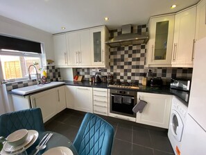 A compact kitchen with white cabinets, a gas stove, a microwave, and a washing machine.