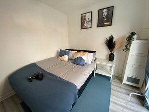 A bedroom with a bed, bedside tables, a dresser, and wall art.