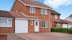 A two-story brick house with a white garage door, a front door, and a small window. - Host Stay Stockenchurch (Milton Keynes)