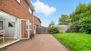 A brick pathway leading to a house with a garage door open, a small table, and chairs outside. - Host Stay Stockenchurch (Milton Keynes)
