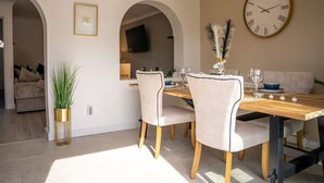 A dining area with a wooden table, two chairs, a clock, and a plant. - Host Stay Glazier Drive (Milton Keynes)