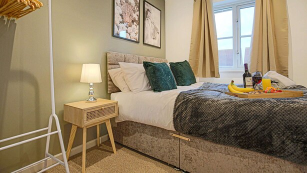 A neatly arranged bedroom with a bed, bedside table, and a window with curtains. - Host Stay Chicksands Avenue (Milton Keynes)
