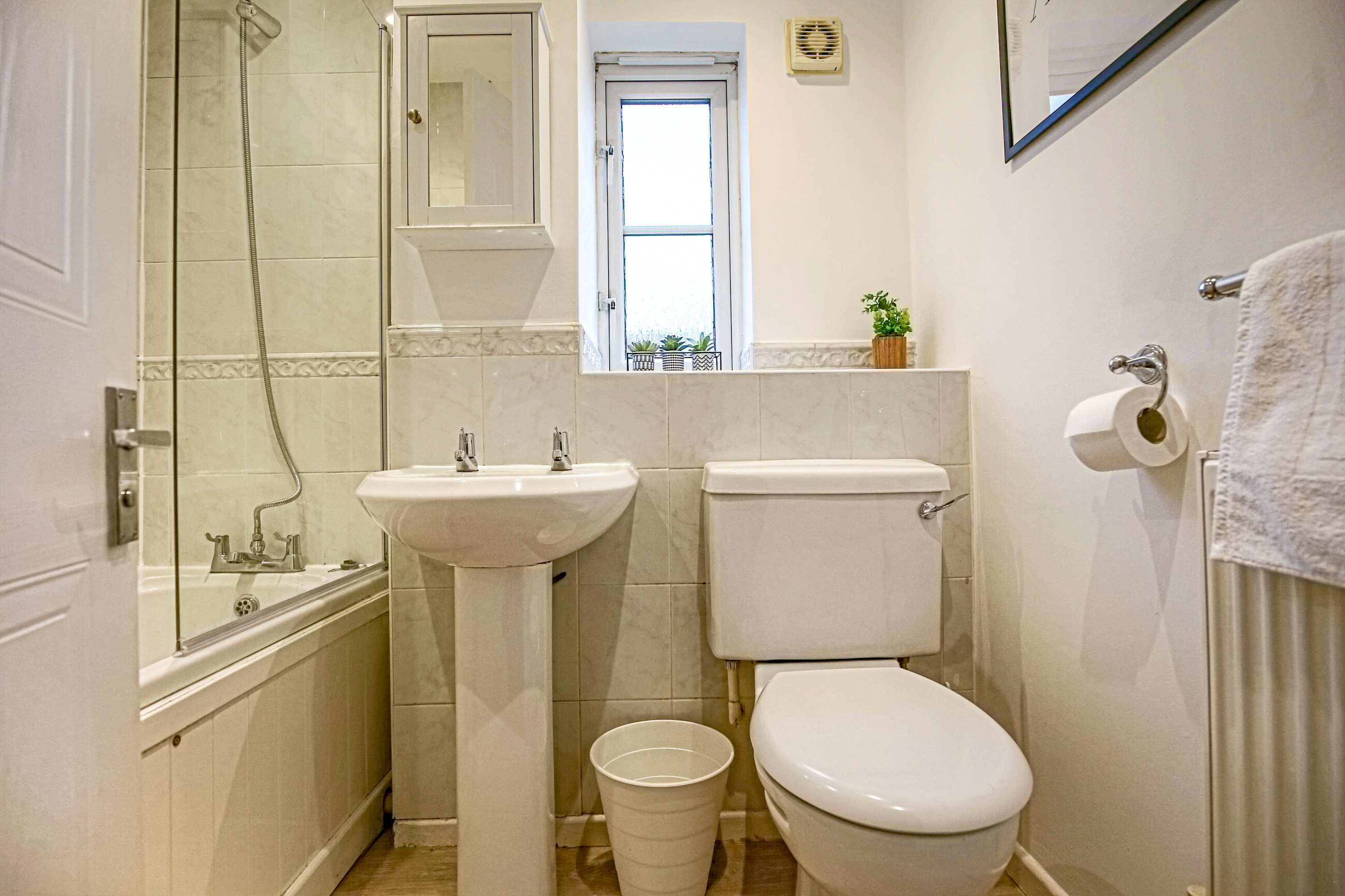 Un baño pequeño con ducha, lavabo, inodoro y un ventanal.