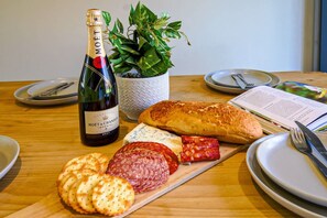 Une table avec une bouteille de champagne Moët & Chandon, un pain, divers fromages et de la charcuterie.