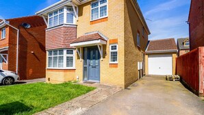 A two-story residential building with a garage, a front door, and a small front yard. - Host Stay Wiltshire Way (Milton Keynes)
