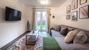Ein modernes Wohnzimmer mit einer Couch, einem Couchtisch und einem an der Wand befestigten Fernseher.