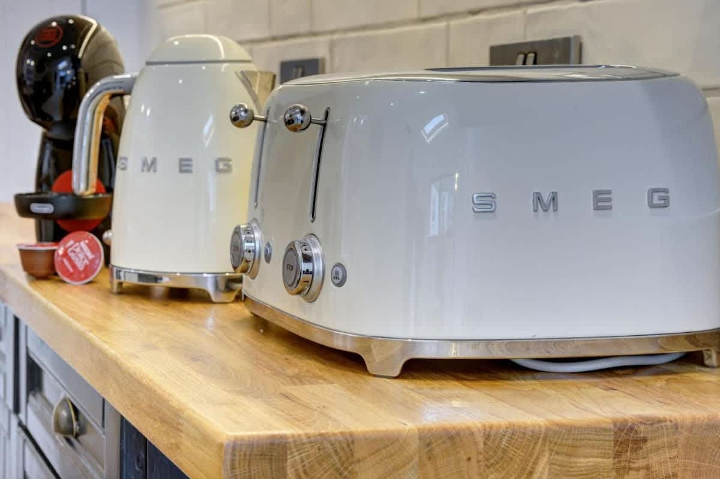 Two white Smeg appliances on a wooden countertop.
