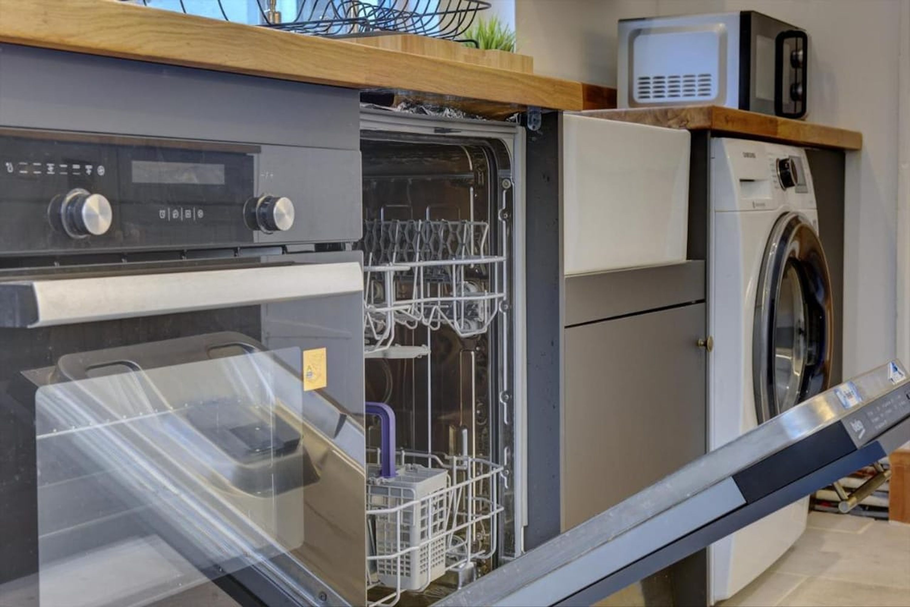 Une cuisine compacte équipée d’un lave-vaisselle, d’un four à micro-ondes et d’une machine à laver.