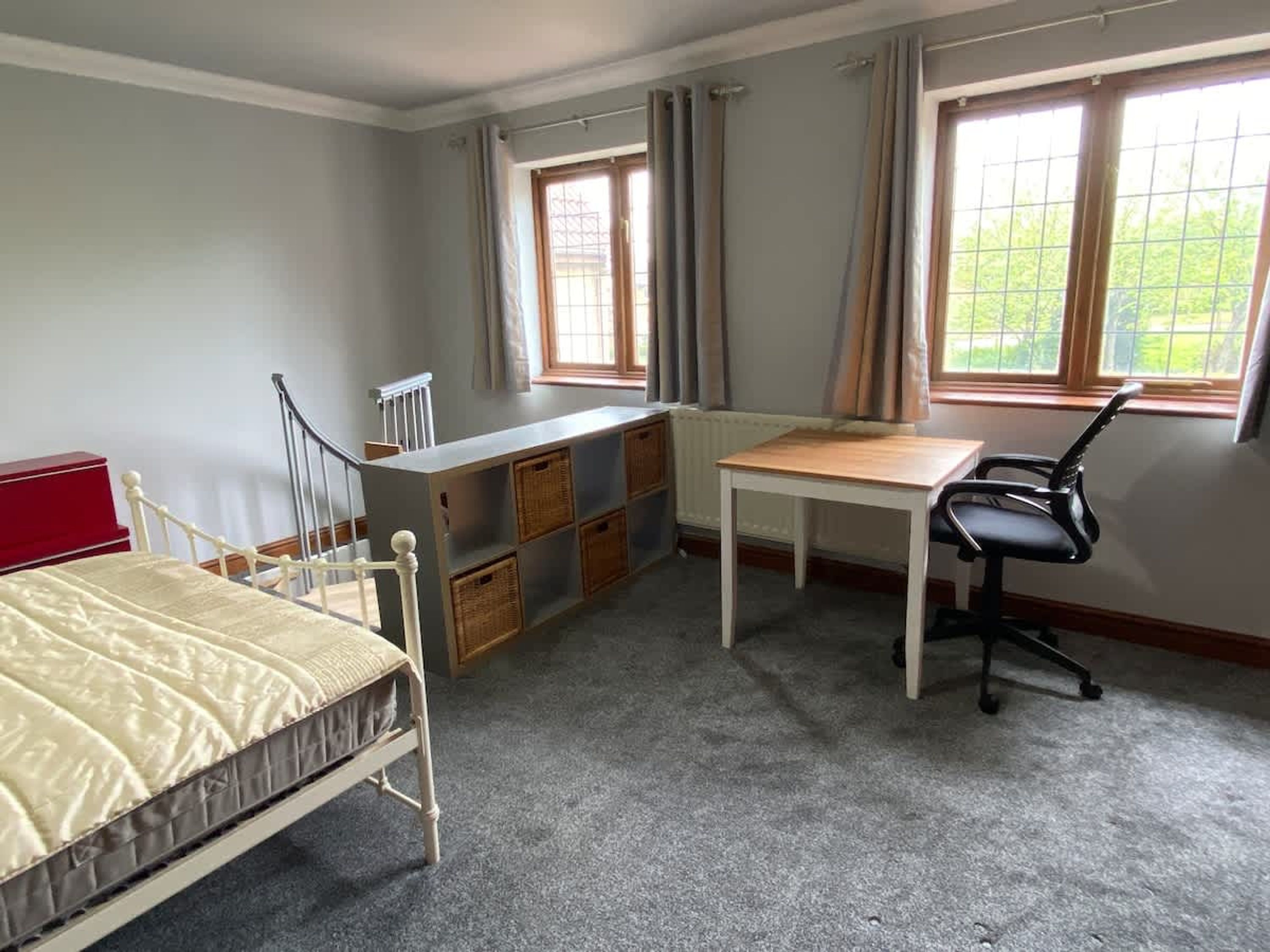 A bedroom with a bed, a desk, a chair, and a radiator.