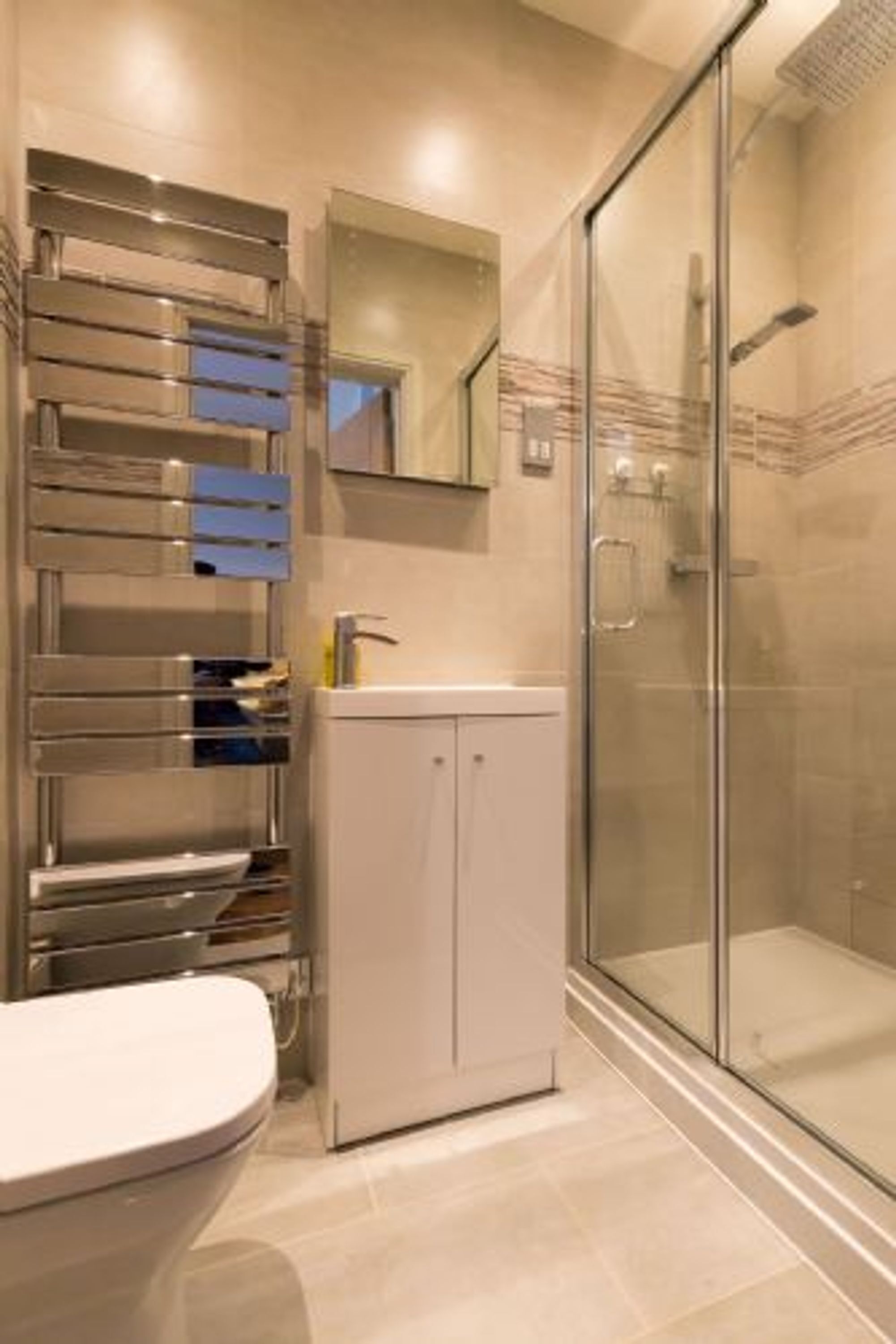 A modern bathroom with a glass shower enclosure, a built-in sink, and a toilet.