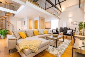 A modern living room with a sectional sofa, a coffee table, and a staircase. - Host Stay Oddfellows Hall (Holt)