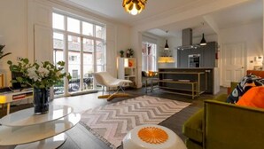 Un salon moderne doté d’une grande fenêtre, d’un coin repas et d’une cuisine.
