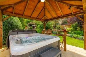 A hot tub under a wooden gazebo in a lush garden. - Host Stay Woodside House (Norwich)